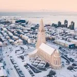 Hallgrimskirkja cathedral church in the center of Reykjavik downtown Iceland. White winter streets covered in snow on the sunset sunrise aerial drone view