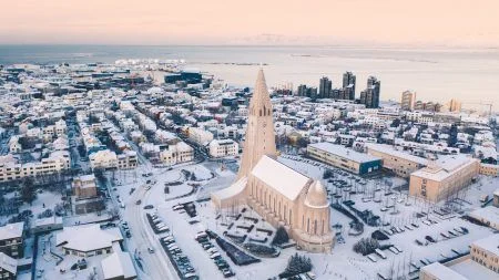 Hallgrimskirkja cathedral church in the center of Reykjavik downtown Iceland. White winter streets covered in snow on the sunset sunrise aerial drone view