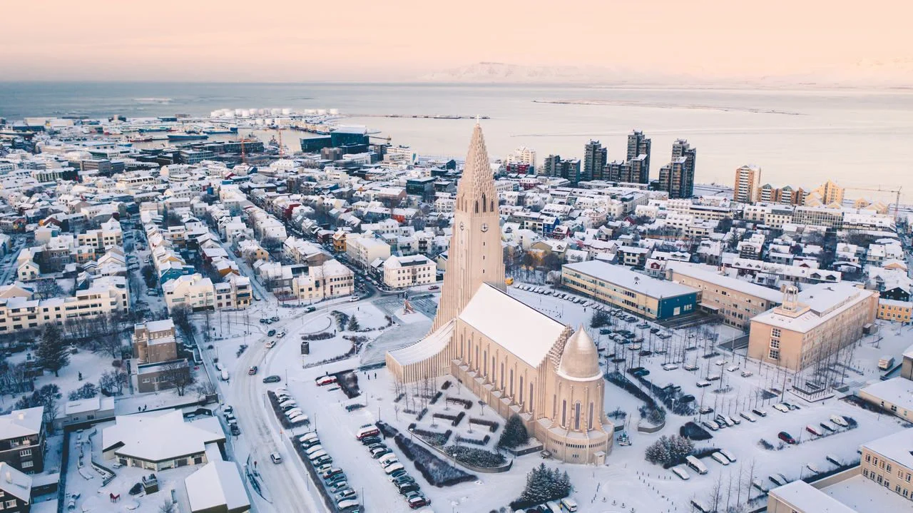 Hallgrimskirkja cathedral church in the center of Reykjavik downtown Iceland. White winter streets covered in snow on the sunset sunrise aerial drone view