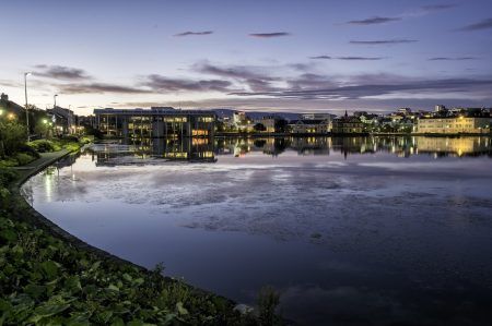 Reykjavik pond shot on a still summer night, Reykjavik city hall and other houses reflected in the still water.
