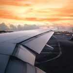 Wing of an airplane taking off in the terminal with clouds at sunset, blank for copy space