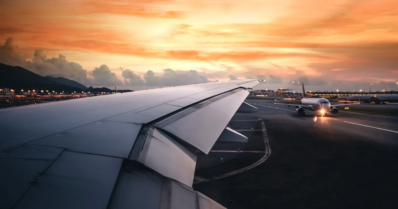 Wing of an airplane taking off in the terminal with clouds at sunset, blank for copy space