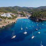 Aerial view of the beach of Port Sant Miquel on the north shore of Ibiza island in Spain – Isolated bay sided with large hillside hotels in the Balearic Islands