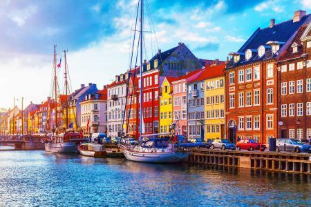 Picturesque summer sunsets view of Nyhavn pier with colorful buildings, ships, yachts and other boats in the Old Town of Copenhagen, Denmark