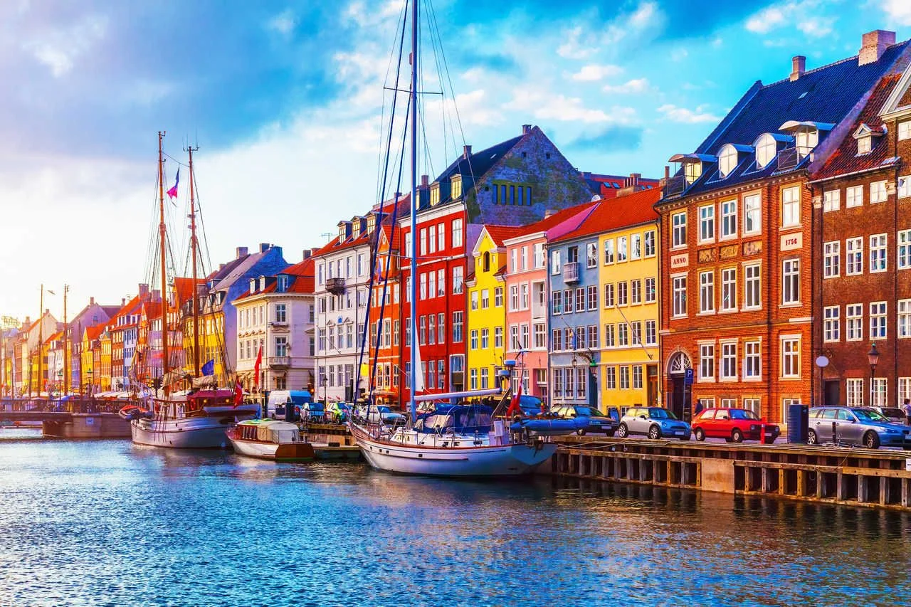 Picturesque summer sunsets view of Nyhavn pier with colorful buildings, ships, yachts and other boats in the Old Town of Copenhagen, Denmark