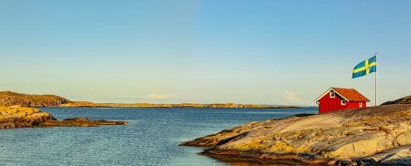 Red house in Sweden on the skerry coast with a flag