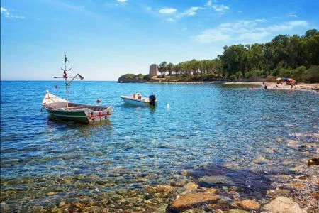 Santa Margherita di Pula (Sardinia) – Cala d’Ostia, crystal clear sea on the bay with a fishing boat.