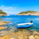 Small fishing boat on shore Cala Portinatx bay, Ibiza island, Spain