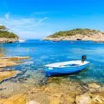 Small fishing boat on shore Cala Portinatx bay, Ibiza island, Spain