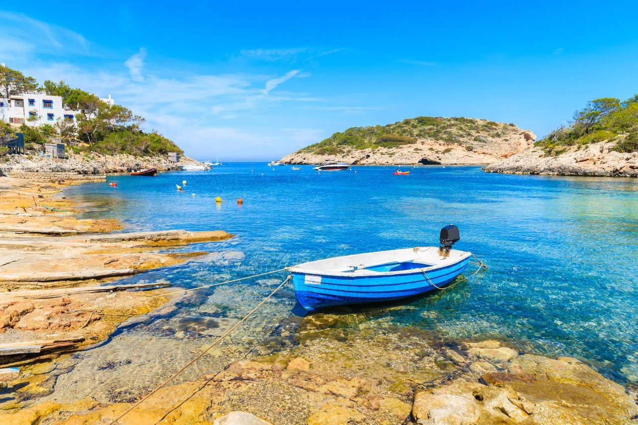 Small fishing boat on shore Cala Portinatx bay, Ibiza island, Spain