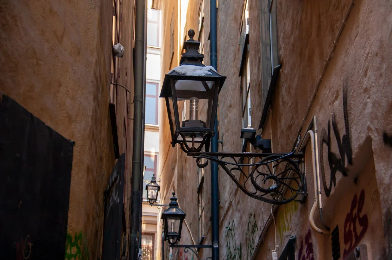 Stylish, metal, black street lamp hanging on a stone facade of a building at the Old Town in Stockholm, Sweden. Selected focus.