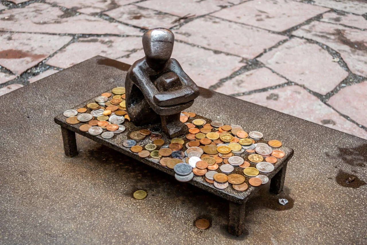Tiny 15cm high but hugely popular public artwork Järnpojke or Iron Boy, looking at the moon, and accepting good luck coins in the Gamla Stan or Old Town district of Stockholm, Sweden