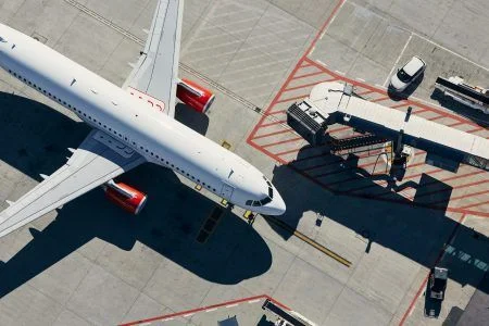 Aerial view of plane. Airplane in front of the passenger boarding bridge from airport terminal.