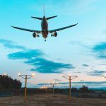 Airplane landing at the airport dusk – Silhouette of a commercial airliner approaching the runway after sunset – Teal and orange filter effect perfect for travel and wanderlust concepts