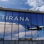 Jet aircraft landing at Tirana, Albania 3D rendering illustration. Arrival in the city with the glass airport terminal and reflection of the plane. Travel, business, tourism and transport concept.