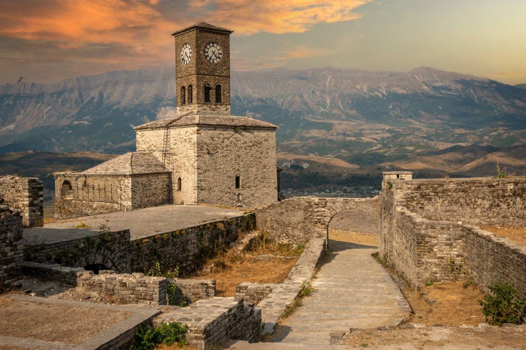 Sunset over clock tower and fortress at Gjirokaster, a beautiful town in Albania where the Ottoman legacy is clearly visible. High above the town the huge castle offers panoramic views.
