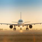 Sunset view of airplane on airport runway under dramatic sky