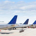 The tails of some aircraft at the airport during on-board operations. There are four planes on a sunny day, with blue skies. Travel and transportation concepts.