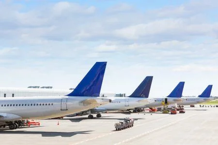 The tails of some aircraft at the airport during on-board operations. There are four planes on a sunny day, with blue skies. Travel and transportation concepts.