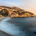 Long exposure of Scenic sunset at Calanque des Eaux Salees or Salt water rocky inlet with pebble beach and old railway bridge near Marseille France