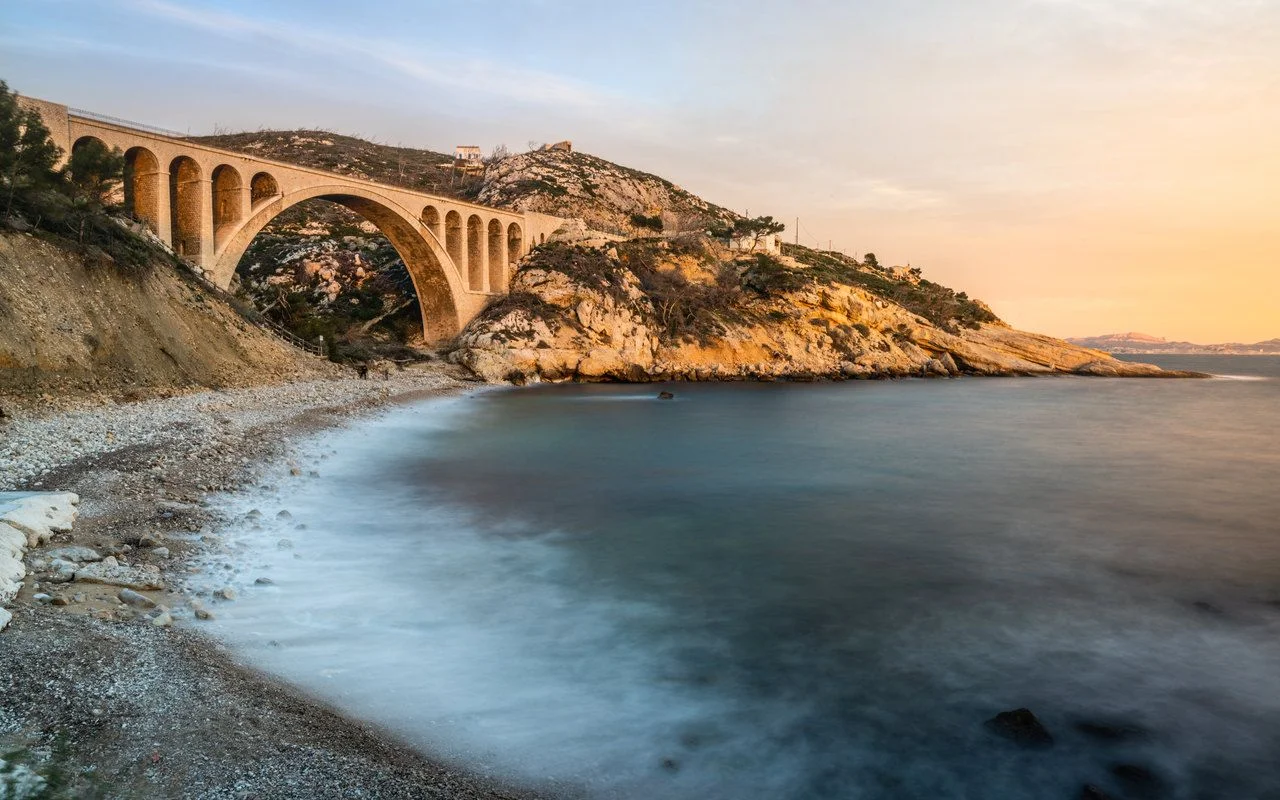 Long exposure of Scenic sunset at Calanque des Eaux Salees or Salt water rocky inlet with pebble beach and old railway bridge near Marseille France
