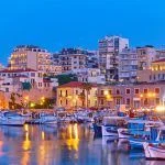 View of Heraklion city with harbour with yachts and fishing boats at dusk, Crete island, Greece. Greek scenery