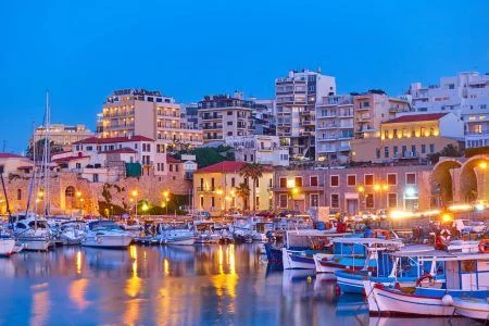 View of Heraklion city with harbour with yachts and fishing boats at dusk, Crete island, Greece. Greek scenery