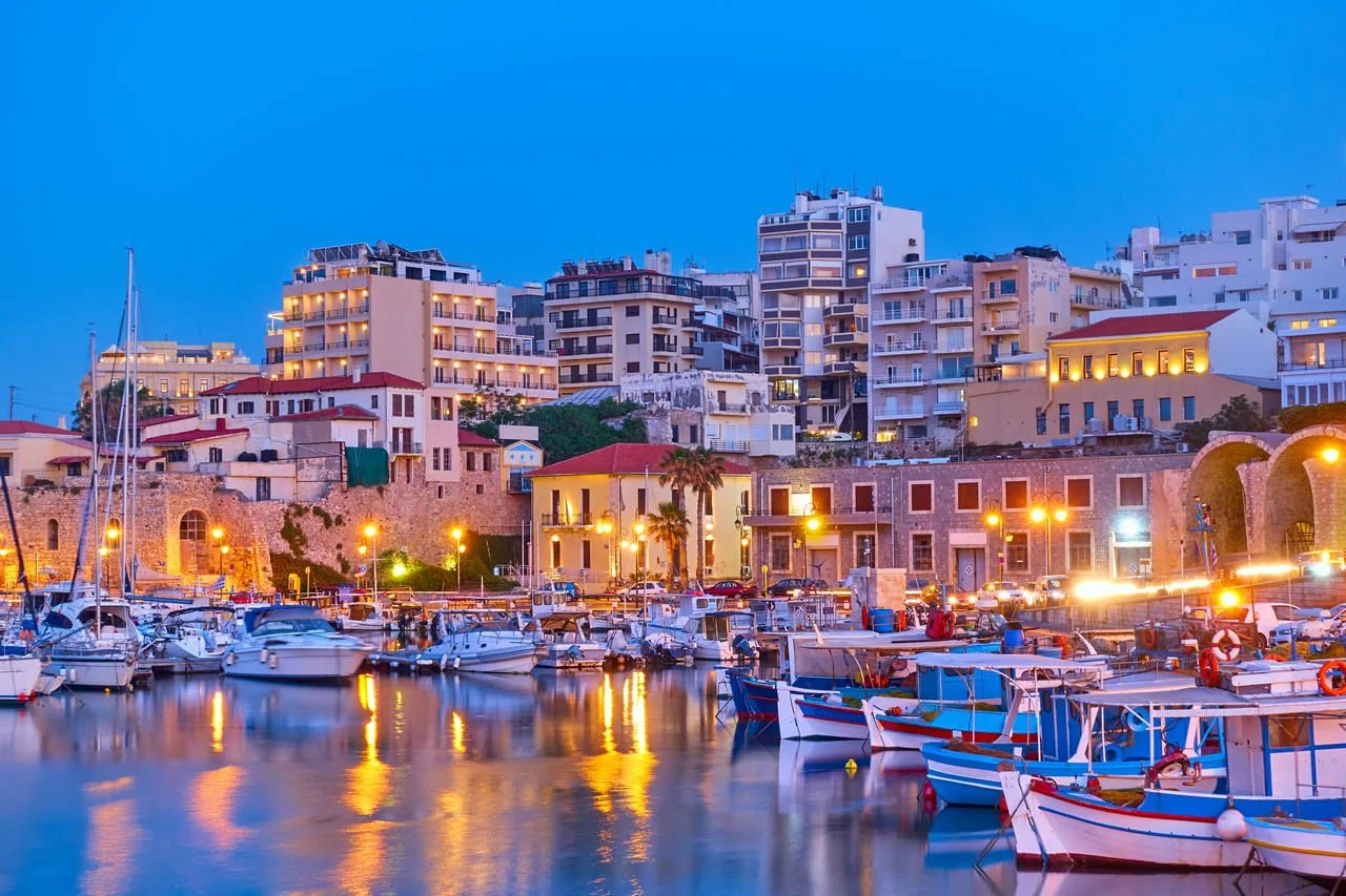 View of Heraklion city with harbour with yachts and fishing boats at dusk, Crete island, Greece. Greek scenery