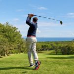 A golfer on a professional golf course. A golfer with a golf club hitting the ball for a perfect shot.