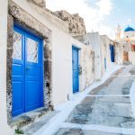 Beautiful street with blue doors of Akrotiri in Santorini, Greece