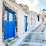 Beautiful street with blue doors of Akrotiri in Santorini, Greece