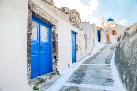 Beautiful street with blue doors of Akrotiri in Santorini, Greece