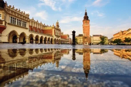 Cloth hall market and the Town Hall tower on Rynek main square in Krakow Old town, Poland, reflecting in the rain puddle_Easy-Resize.com