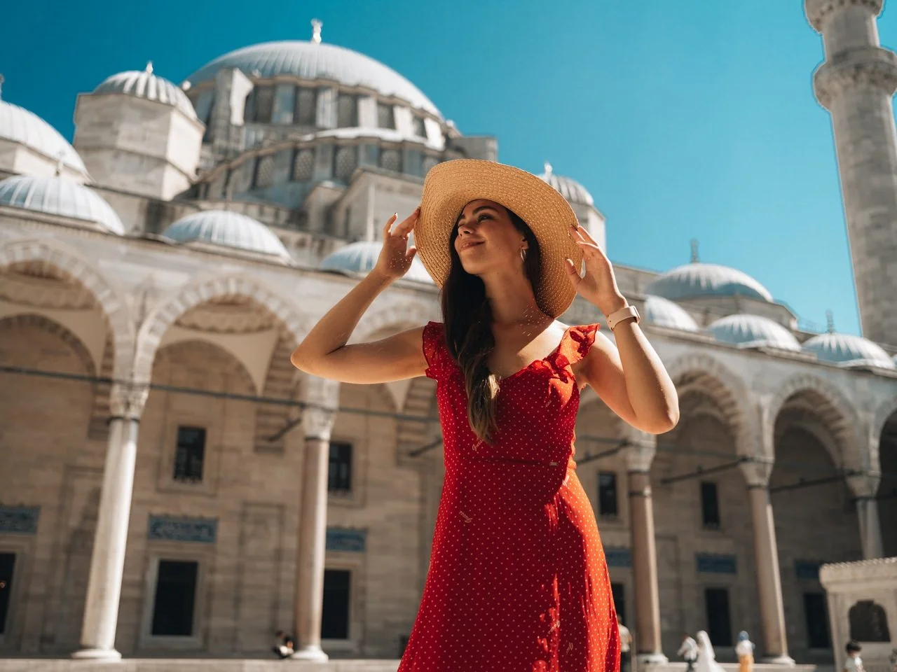 A beautiful travel blogger girl in a long red dress and a straw hat is photographed at the ancient sights in Istanbul in Turkey.