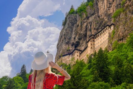 Tourist woman watches Sumela Monastery in Trabzon, Turkey. Sumela Monastery is one of the best tourist attraction in Black Sea region of Turkey
